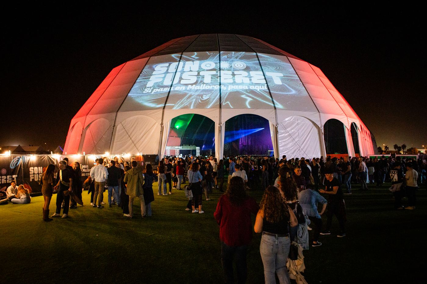 La carpa iluminada de noche con la marca proyectada sobre la lona